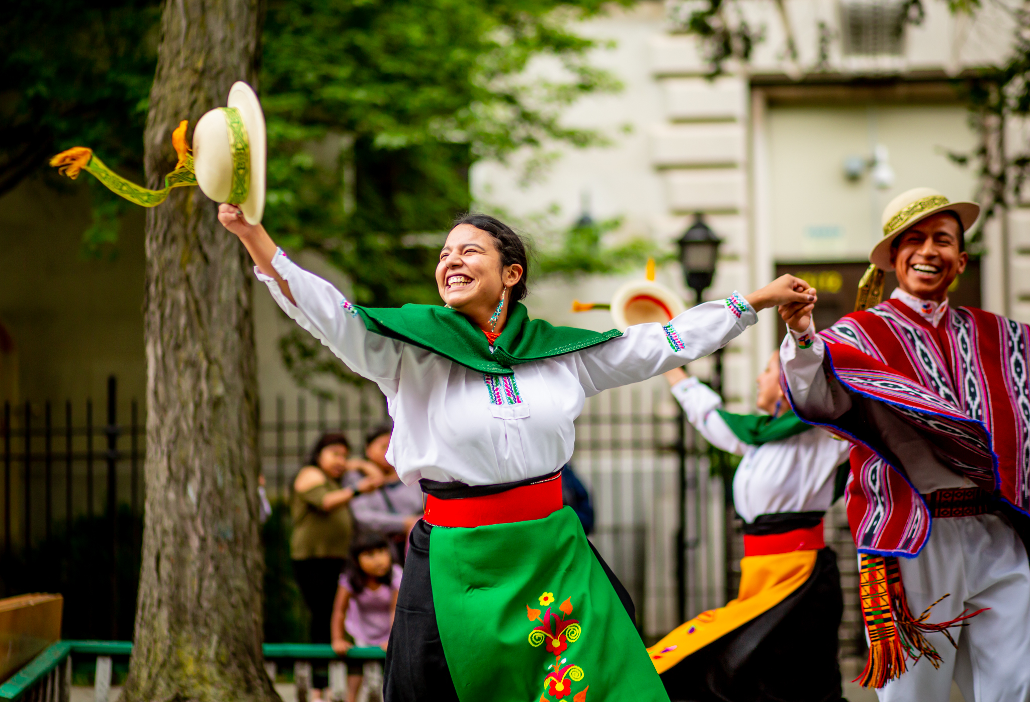 Ecuadorian dancer in white and green smiling and holding hat