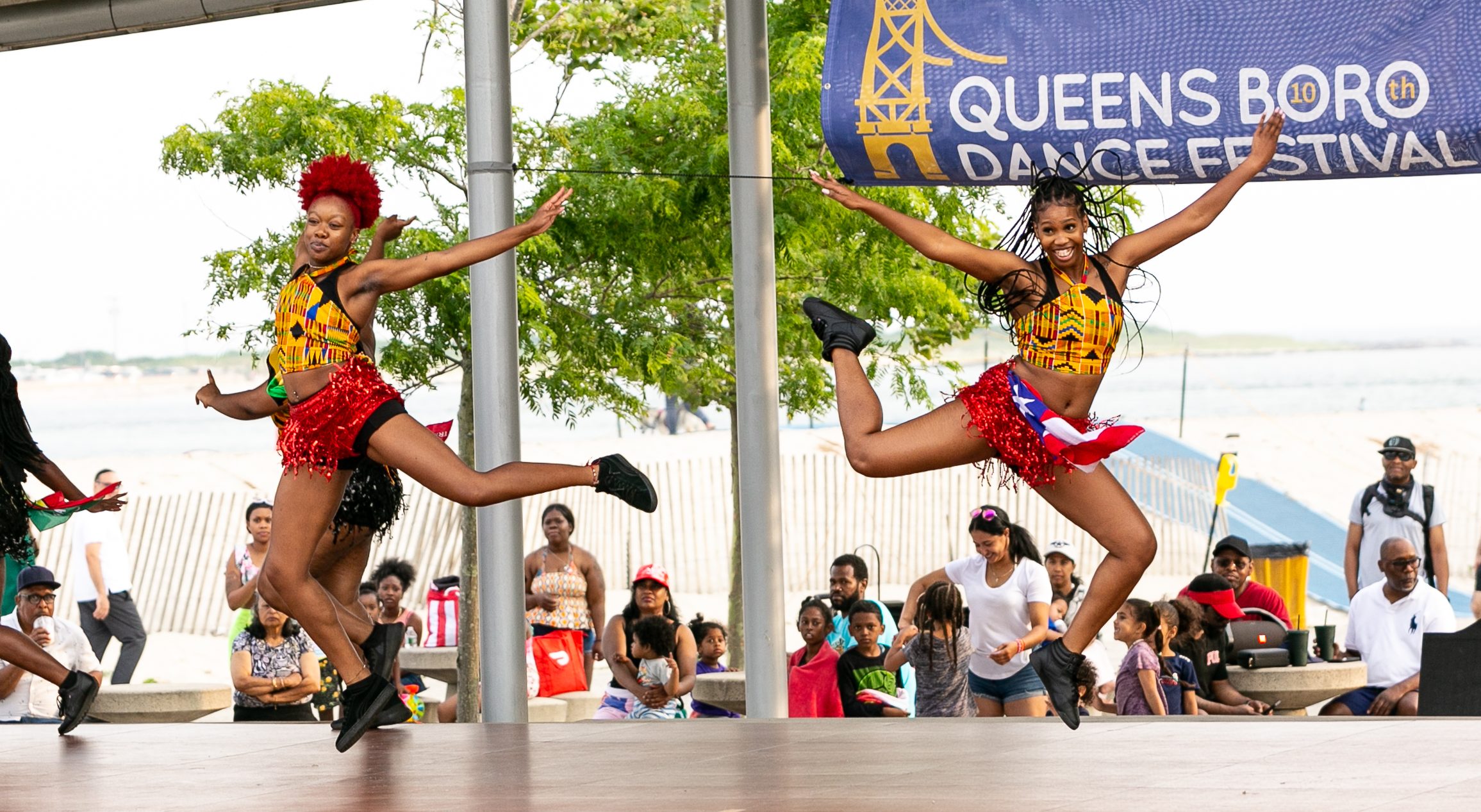 Two Caribbean dancers leaping and smiling