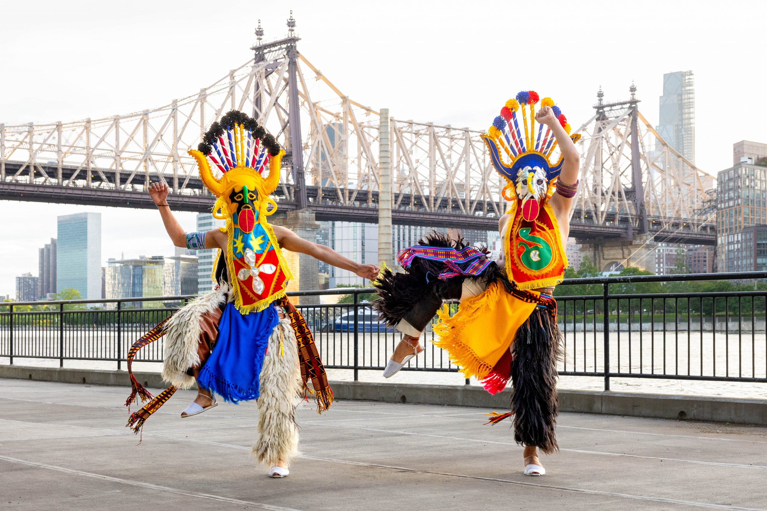 2 male Ecuadorian dancers wearing colorful headresses and pants